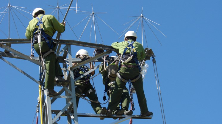Operarios en torre de alta tensión realizando tareas de mantenimiento