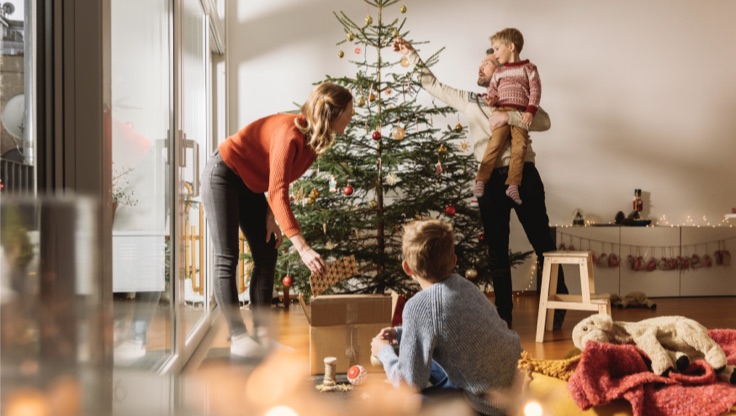 Imagen de familia decorando árbol de navidad